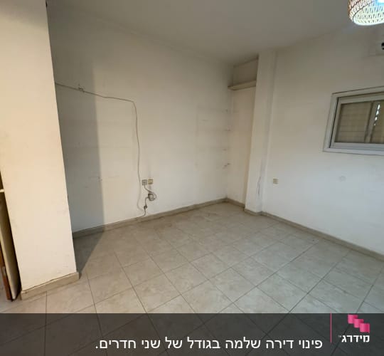 חדר ריק עם רצפת אריחים וקיר לבן